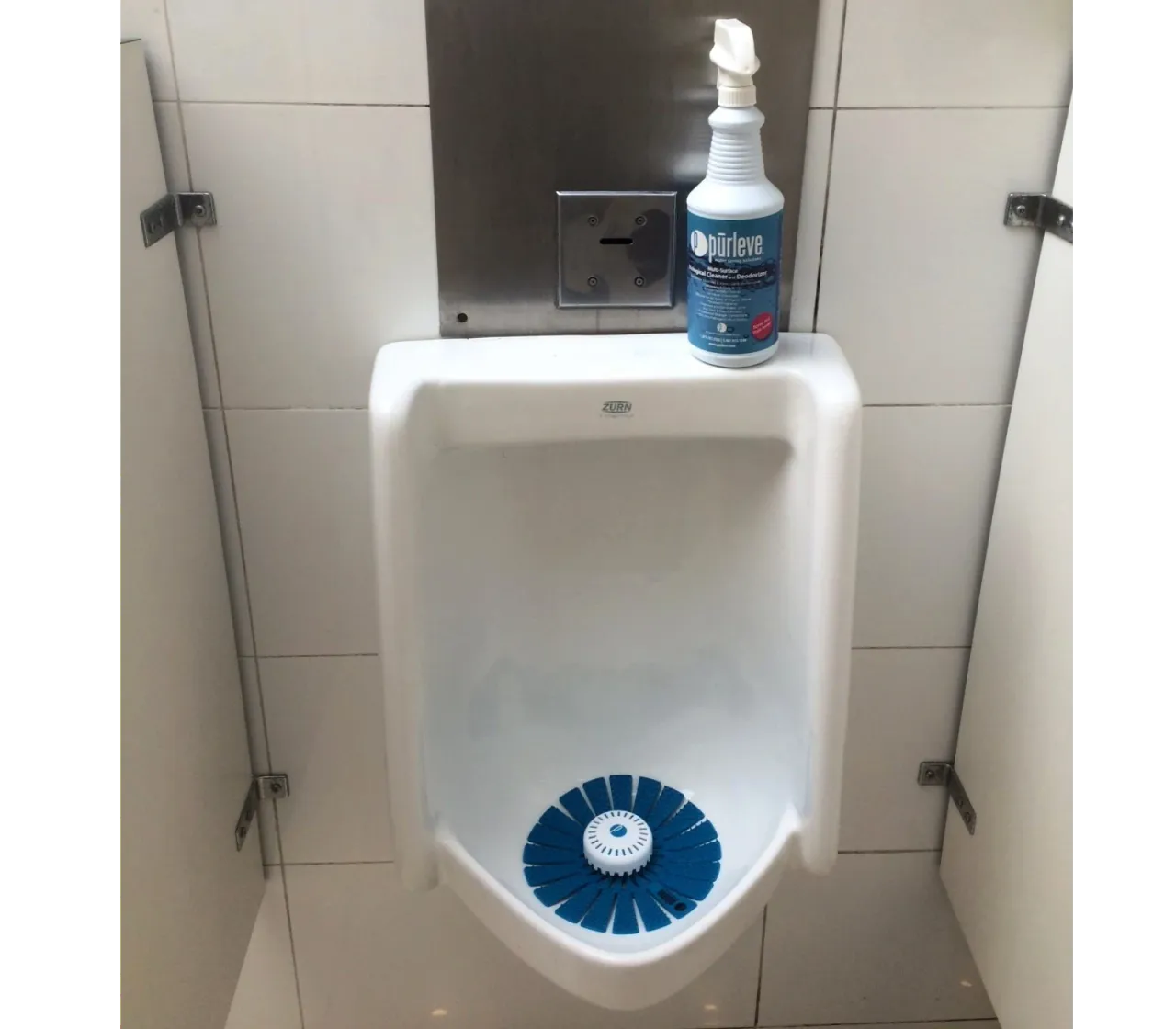 Urinario con pantalla azul y un envase de limpiador junto al sistema de descarga