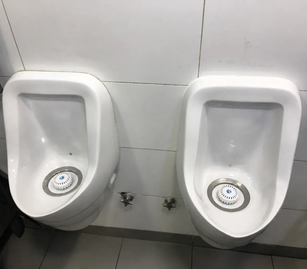 Dos urinarios instalados sobre un muro de cerámica